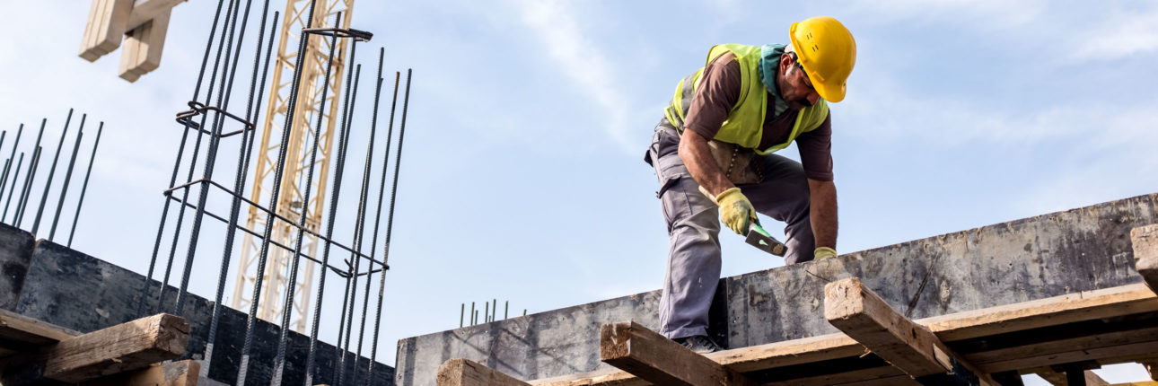 A construction worker on a building site with a crane in the background