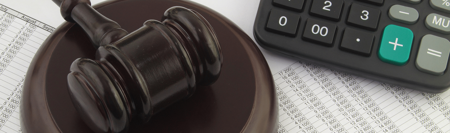 A judge’s gavel rests on financial documents next to a calculator.